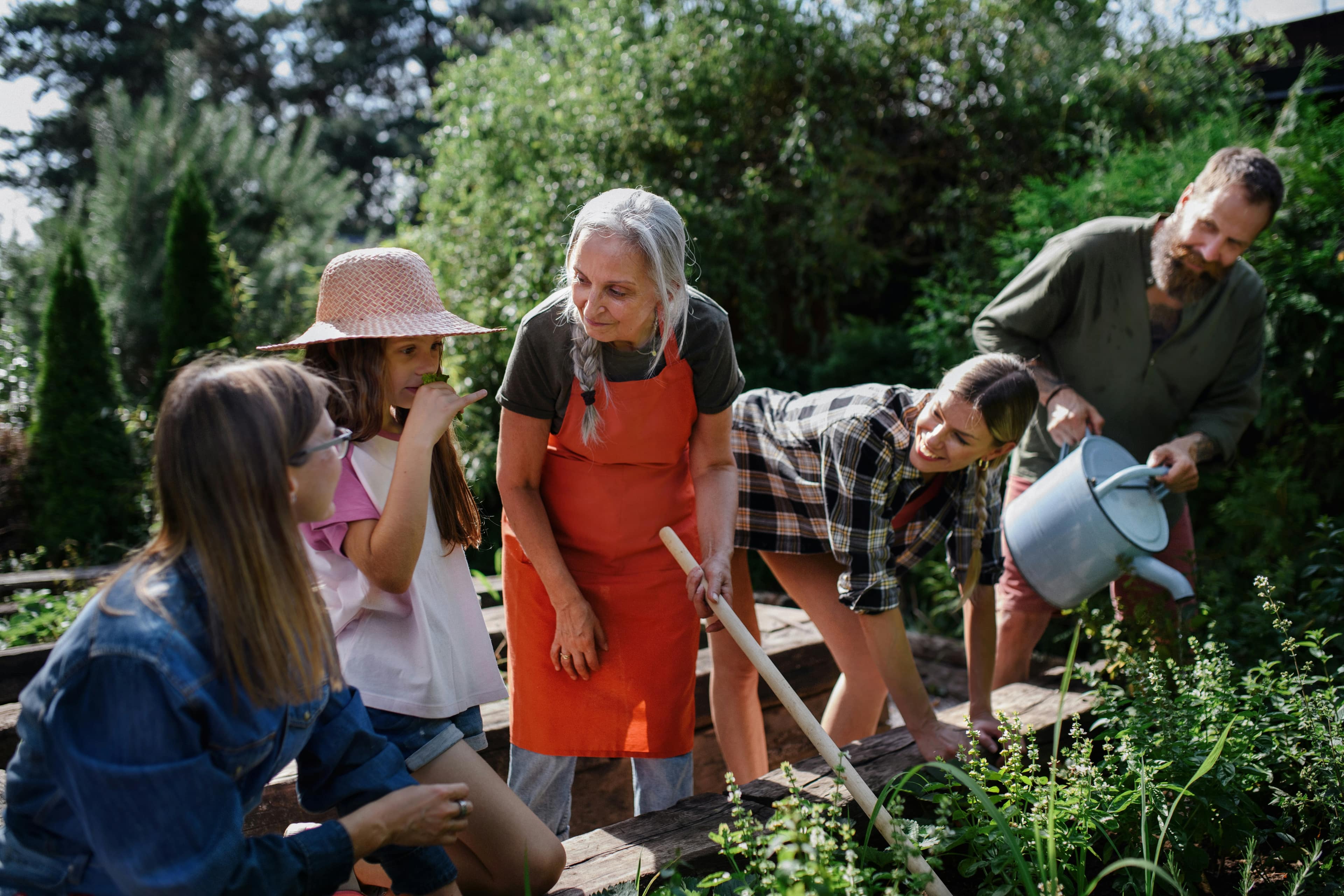 Three generations of a family gardening together on a sunlit afternoon.